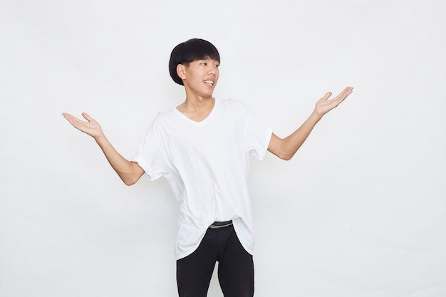 Emocionado sorprendido lindo joven asiático en camiseta blanca casual haciendo gesto con la mano abierta sobre la superficie gris