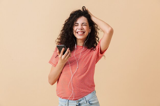 Emocional feliz animada jovem cacheada ouvindo música