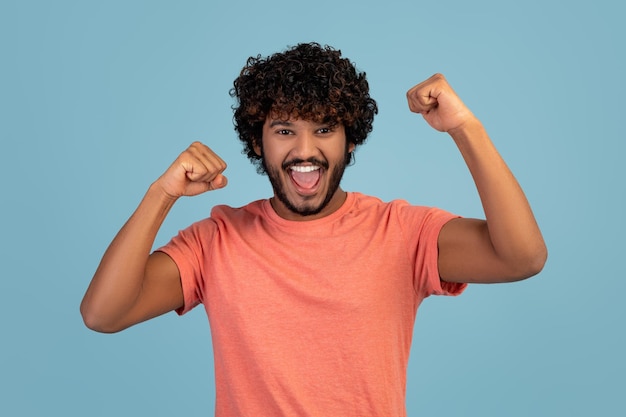 Emocional índio cerrando os punhos comemorando o sucesso em azul