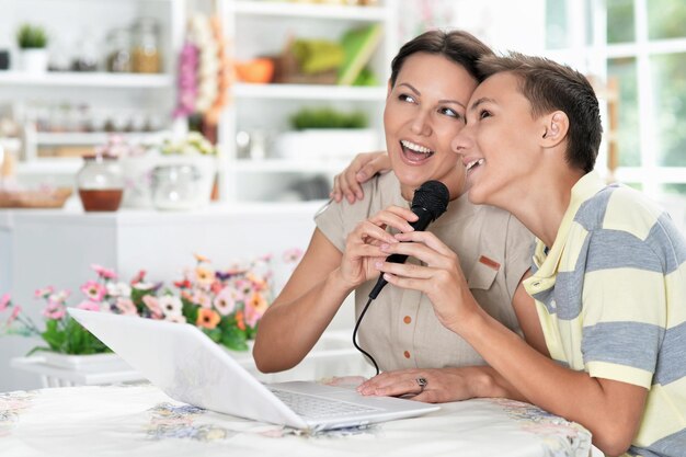 Emocional mãe e filho cantando karaokê com laptop moderno