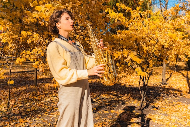 Emocional tocando el saxofón en el parque de otoño