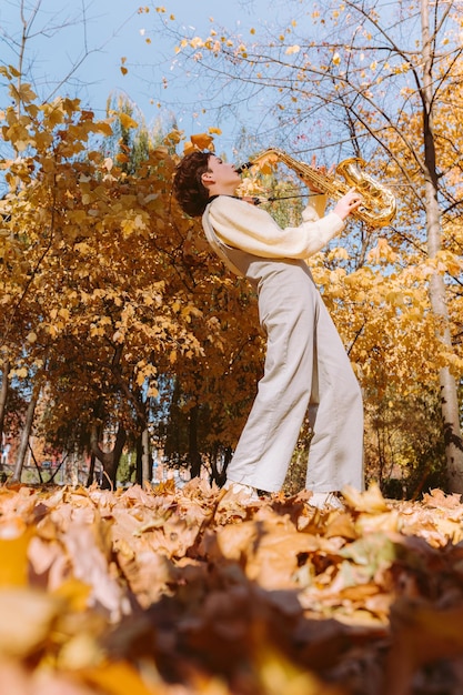 Foto emocional tocando el saxofón en el parque de otoño