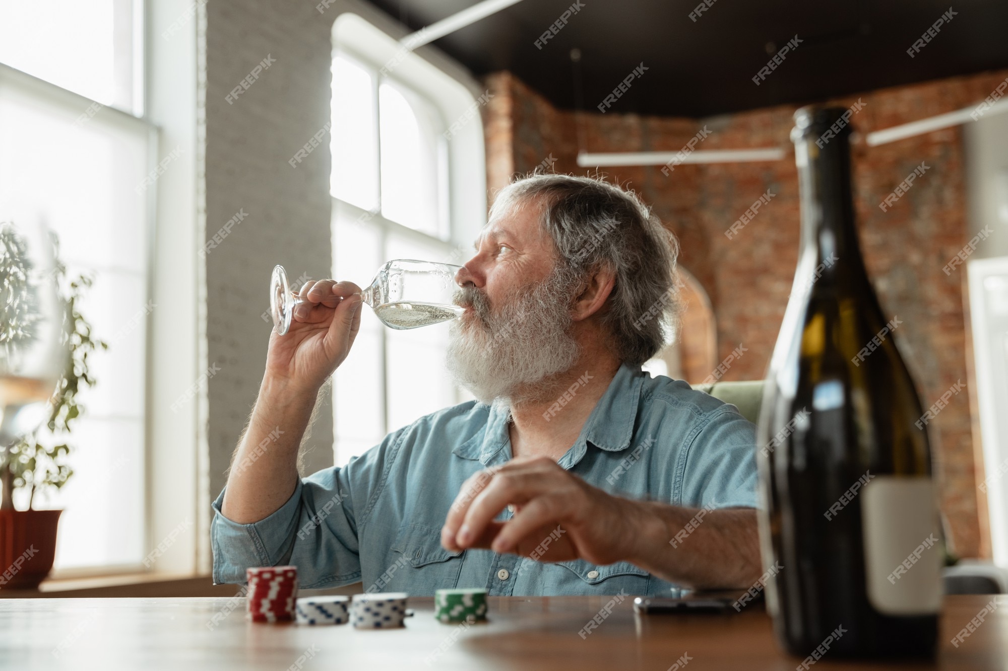 Emocionante. homem maduro feliz bebendo vinho com amigos durante o jogo de  cartas. parece encantado, animado. homem caucasiano, jogos de azar em casa.  emoções sinceras, bem-estar, conceito de expressão facial. boa velhice.