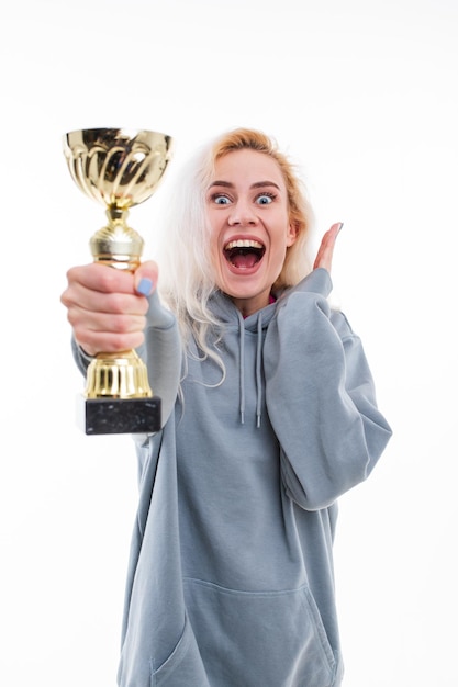 Foto emociones de una atleta femenina después de ganar una competencia la modelo sostiene la copa de oro de la competencia en sus manos