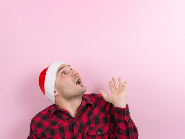 Emociones en la cara, miedo, recuerdos de vacaciones, negativo. Un hombre en un conejo a cuadros y un sombrero rojo de Navidad