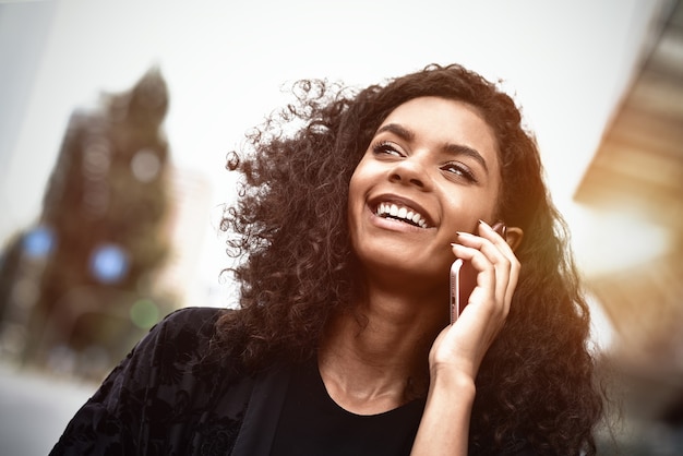 Emociones positivas. Concepto de estilo de vida. Cerca de joven mujer de raza mixta utilice un teléfono.