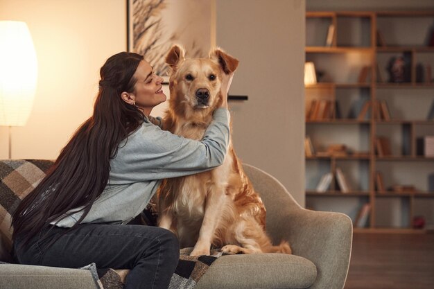 Foto emociones positivas jugando juntos la mujer está con el perro golden retriever en casa