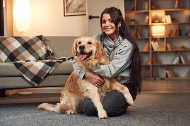 Foto emociones positivas jugando juntos la mujer está con el perro golden retriever en casa