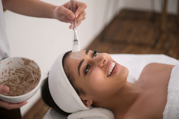 Emociones positivas. Mujer atractiva alegre sonriendo mientras tiene un procedimiento de belleza en el salón de belleza