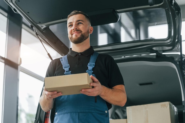 Emociones positivas El repartidor en uniforme está adentro con auto y con orden