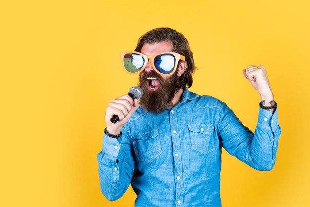 Emociones puras que tengas unas felices fiestas diviértete en la fiesta cantante masculino cantando una canción en el micrófono celebra la fiesta de aniversario hipster hombre con barba con gafas concepto de música