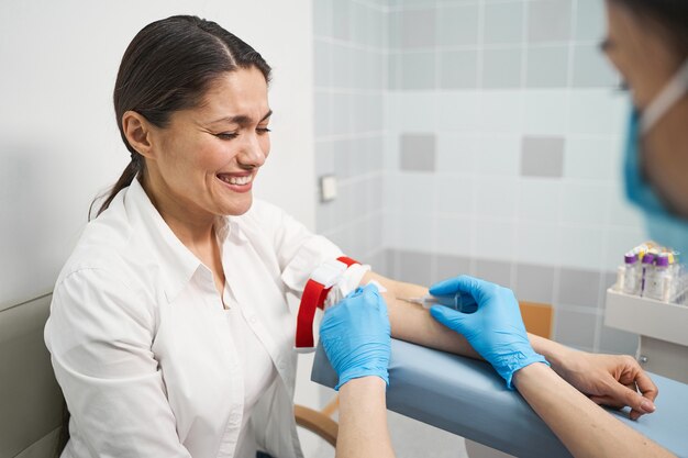 Emociones sinceras. Alegre mujer morena manteniendo los ojos cerrados mientras apoya el brazo