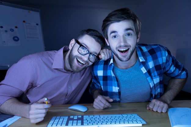 Emoções agradáveis. Homem bonito e feliz, positivo, olhando para a tela do laptop e rindo ao ver algo engraçado