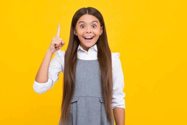 Emoções alegres de rosto animado de menina adolescente Feche o rosto engraçado de um jovem adolescente apontando para cima com o dedo no fundo amarelo A menina tem uma ótima ideia nova Aluna engraçada garoto gênio nerd