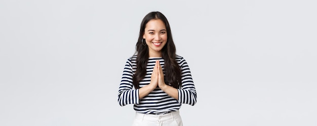 Emoções de pessoas de estilo de vida e conceito casual Linda garota asiática em roupa casual sorrindo como dizendo namastê de mãos dadas em oração implorando ou cumprimentando os hóspedes com uma reverência educada