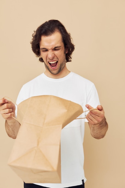 Emoções de saco de papel de homem atraente posando estilo de vida inalterado