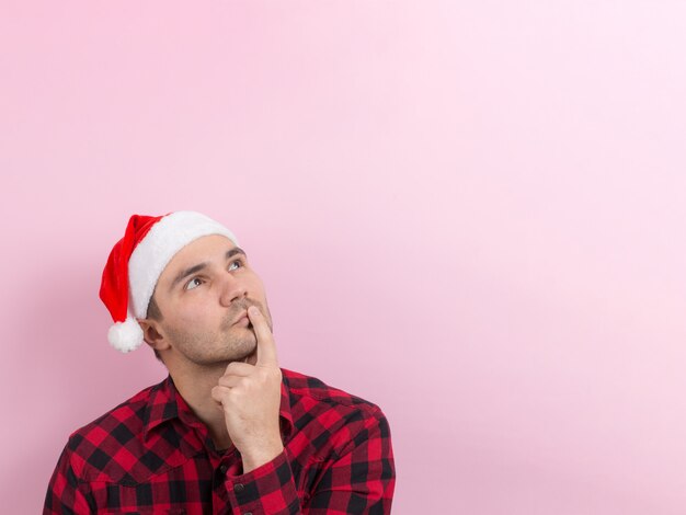 Emoções no rosto, pensativo, reflexão, plano, idéia. um homem em um coelho xadrez e um chapéu vermelho de natal