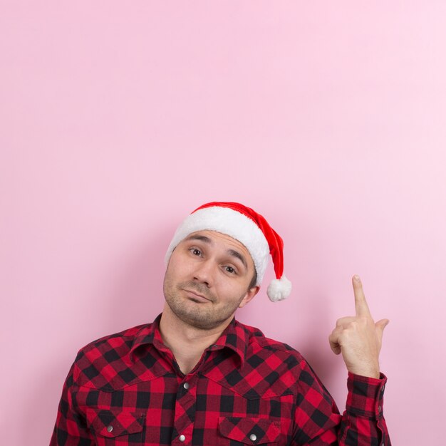 Emoções no rosto, sorriso, alegria. Um homem em um coelho xadrez e um chapéu vermelho de Natal