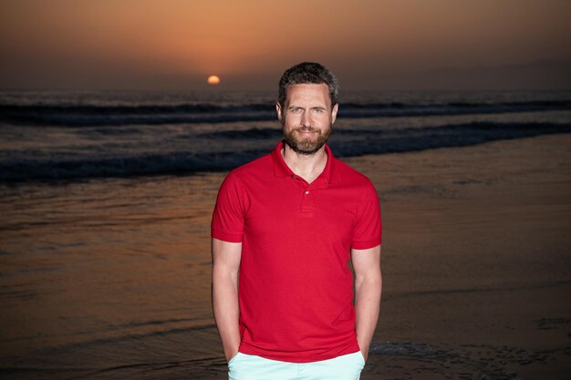 Emoções positivas de férias de verão sorrindo homem com barba no pôr do sol sobre o mar