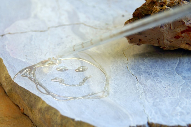 Emoticon de sonrisa pintado por agua sobre la piedra, piedras mojadas. Concepto de geología y pruebas con cloruro en laboratorio.