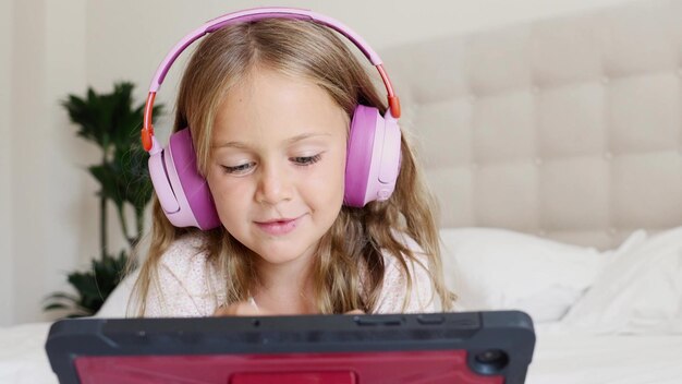 Emotion aufgeregt Lächeln Kind in Kopfhörern spielt digitale Tablet-Computer zu Hause Anwendung.