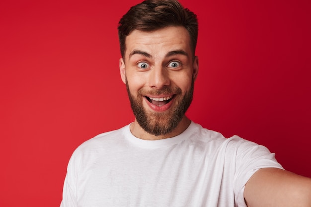 Emotional aufgeregter junger hübscher Mann machen eine Selfie schauende Kamera.