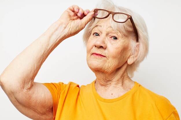 Emotionale ältere Frau in lässigem T-Shirt und Brille auf hellem Hintergrund