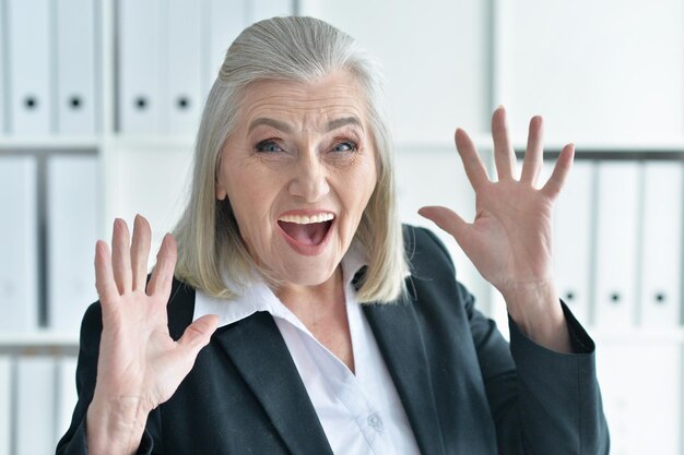 Emotionale alte Geschäftsfrau im Büro posiert vor der Kamera