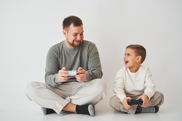 Emotionale Familie spielt Konsolenspiele auf weißem Hintergrund Vater und Sohn spielen Gamepad-Spiele zusammen