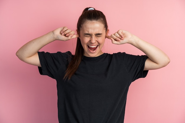 Emotionale junge Frau, die ihre Ohren mit den Fingern bedeckt