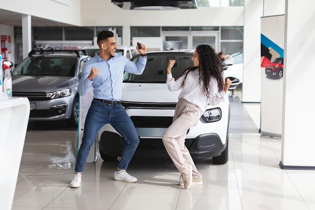 Emotionale Liebhaber aus dem Nahen Osten tanzen beim Kauf eines neuen Autos