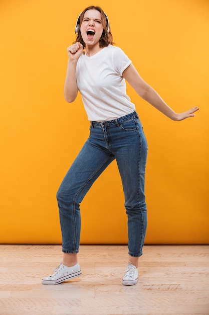 Emotionale lustige junge Frau, die Musik singend hört.