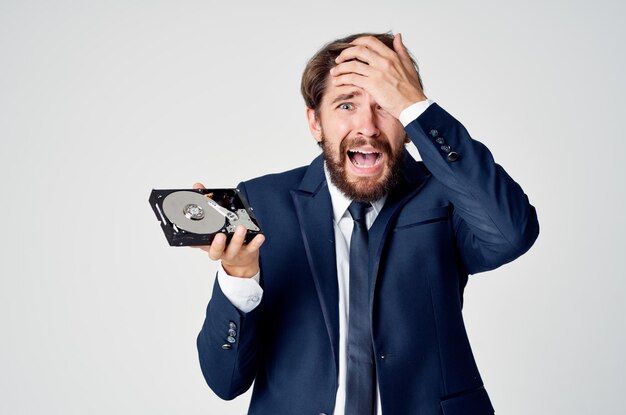 Emotionaler Geschäftsmann mit Festplatte auf Computertechnologie