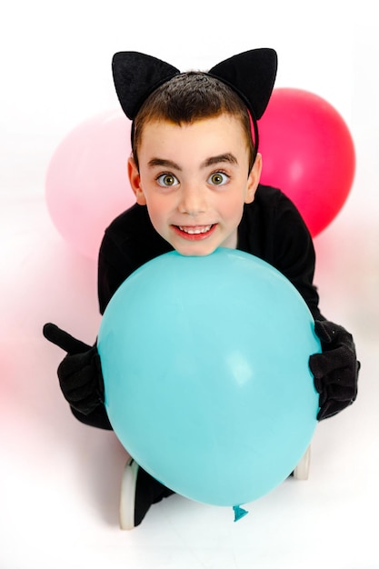 Foto emotionaler junge, verkleidet als schwarze katze mit einem blauen ballon, isoliert purim halloween