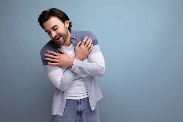 Emotionaler junger brutaler Brunette-Typ auf Studiohintergrund für ein Poster