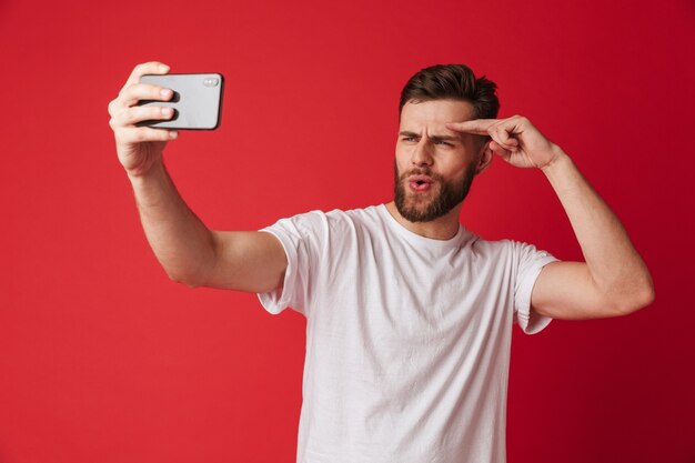 Emotionaler junger Mann macht Selfie per Handy.