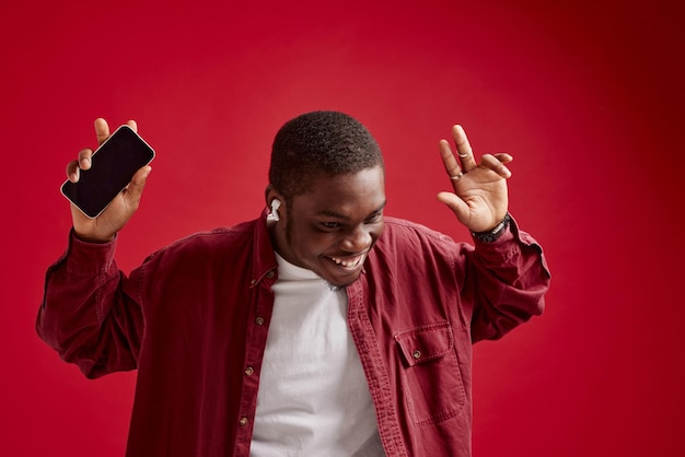 Emotionaler Mann mit afrikanischem Aussehen und Telefon in der Hand. Technologie-Kommunikationsfreude