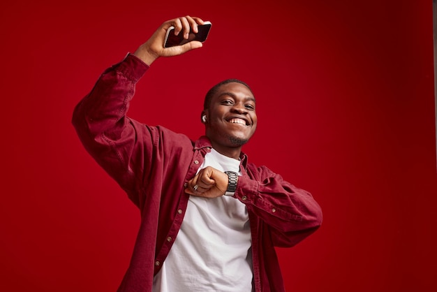 Emotionaler Mann mit afrikanischem Aussehen und Telefon in der Hand. Technologie-Kommunikationsfreude