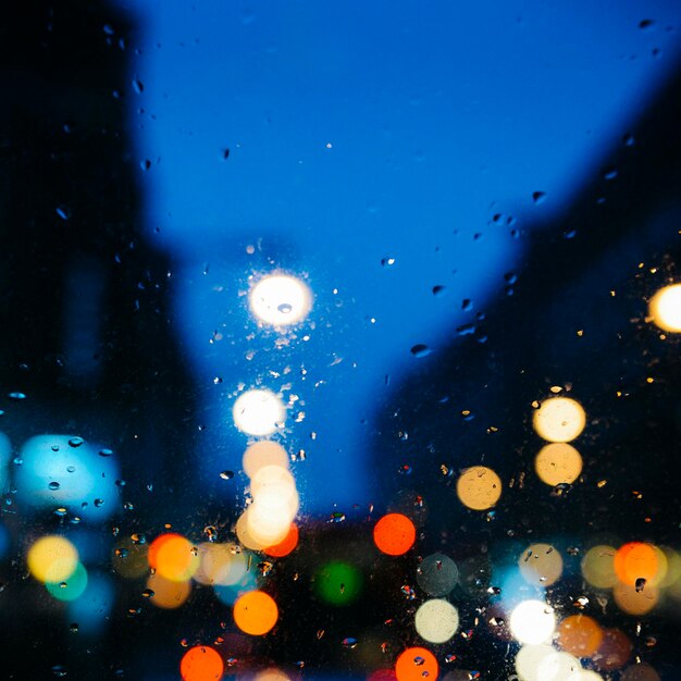Emotionaler melancholischer abstrakter Hintergrund mit defokussierten Lichtern Bokeh in London UK hinter Regentropfen im Fensterglas Konzentrieren Sie sich aufgrund der geringen Schärfentiefe auf wenige Tropfen