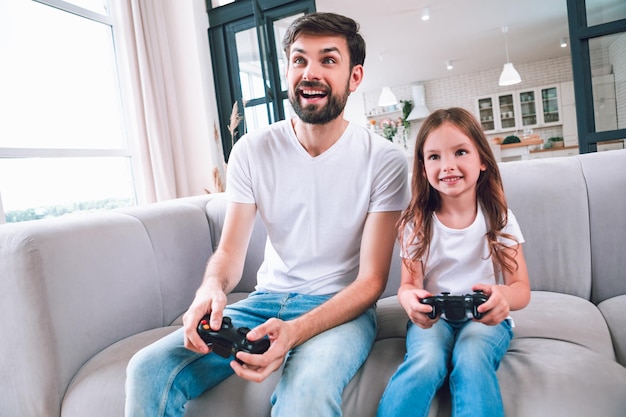 Emotionaler Vater und Tochter, die zusammen Computerspiel im Wohnzimmer spielen