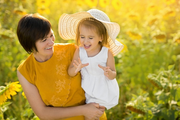 Emotionales Foto einer Großmutter und einer Enkelin in einem Feld von Sonnenblumen