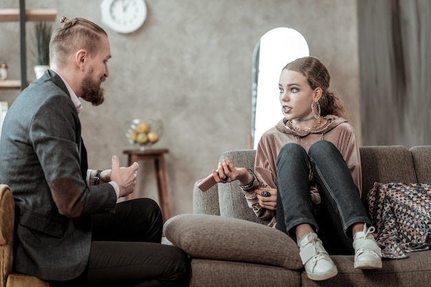 Emotionales Gespräch. Stilvolles Teenager-Mädchen mit dunklem Make-up, das emotionales Gespräch mit Berater hat