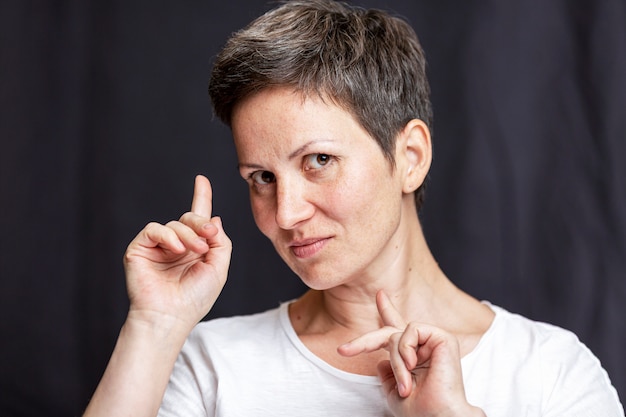 Emotionales Porträt einer erwachsenen Frau mit dem kurzen Haar. Schwarzer Hintergrund.