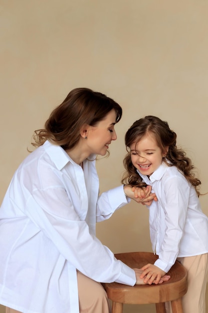 Emotionales Porträt einer fröhlichen Mutter und Tochter in klassischer Kleidung