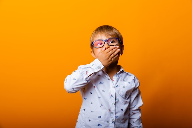 Emotionales Porträt eines Jungen mit Brille. Ein überraschtes Kind schaut in die Kamera.