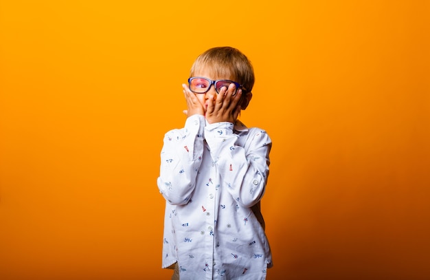 Emotionales Porträt eines Jungen mit Brille. Ein überraschtes Kind schaut in die Kamera.