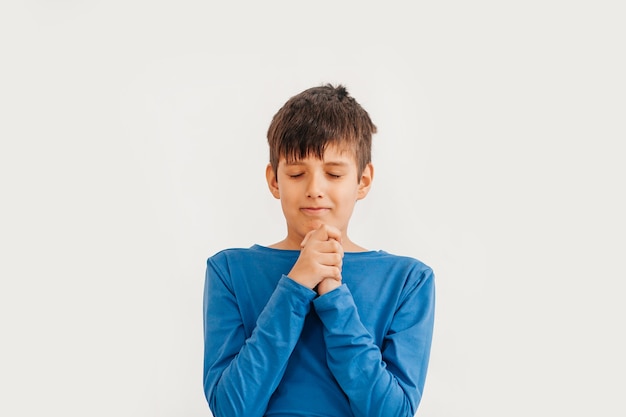 Emotionales Porträt in halber Länge des kaukasischen Teenagerjungen, der blaues T-Shirt trägt. Überraschter Teenager, der Kamera betrachtet. Hübsches glückliches Kind, getrennt auf weißem Hintergrund.