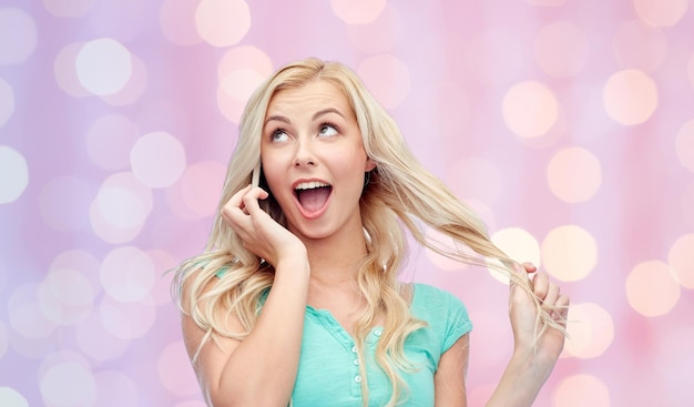 Emotionen, Ausdrücke, Technologie und Personenkonzept - lächelnde junge Frau oder Teenager-Mädchen, die Smartphone über rosafarbene Feiertage anruft, beleuchtet Hintergrund
