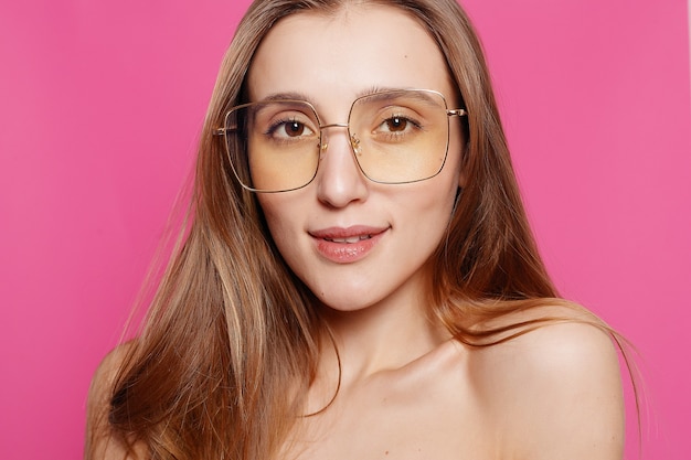 Emotionen, Mode, Menschen, Jugend und Schönheitskonzept - Nahaufnahmeaufnahme der stilvollen jungen Frau in der Sonnenbrille, die gegen rosa Oberfläche lächelt