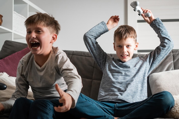 Emotionen vom Gewinnen und Verlieren des Spielwettbewerbs Jungen im Schulalter sitzen mit Joysticks auf dem Sofa Kinder spielen Videospiele